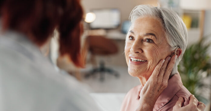 Doctor, senior woman and hearing aid in clinic for geriatric support, tinnitus and help for sound waves. Ent, otolaryngology and patient with cochlear implant for audio, healthcare and auditory tech